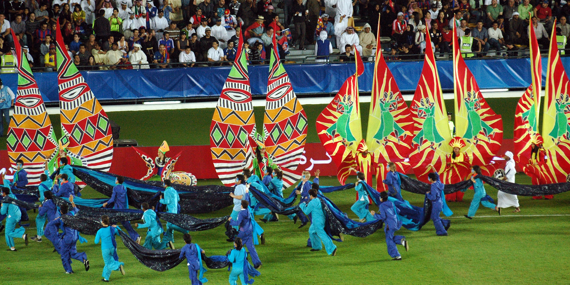 Large silk carnival costumes on a football pitch