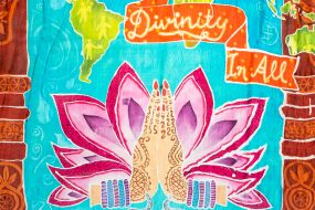 Pink, purple and turquoise illustration of two hands pressed together in greeting in front of a lotus flower