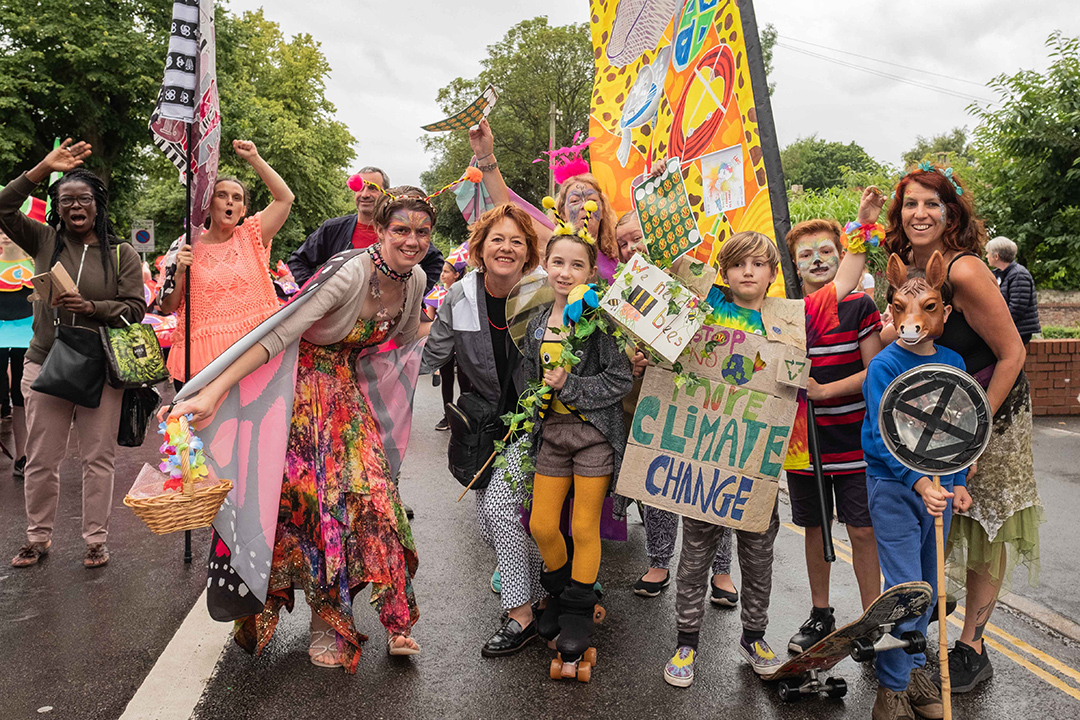 Norwich flags on parade with group of young people holding climate change sign