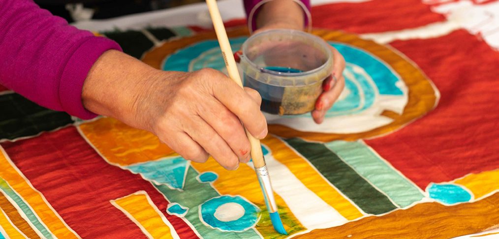 A colourful piece of silk is painted by hand