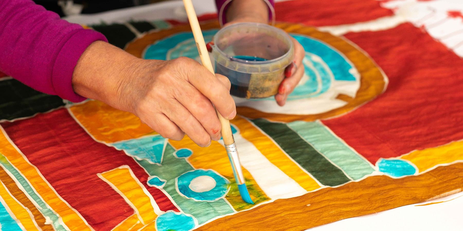 A colourful piece of silk is painted by hand